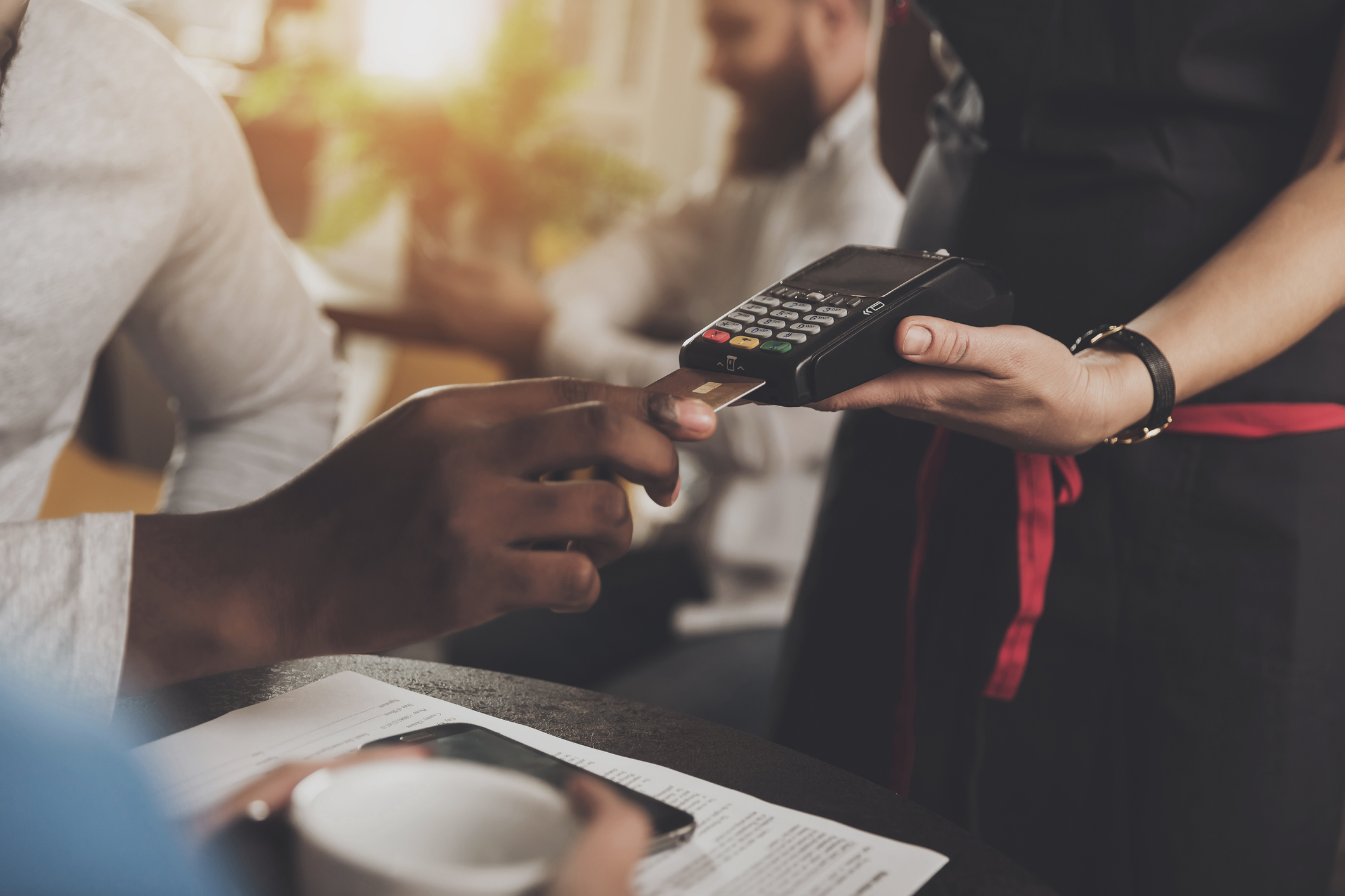 Young African American is calculated credit card. Close-up of a Afro-American man paying for an order in a cafe with a credit card.. The concept of restaurant business and customer service.